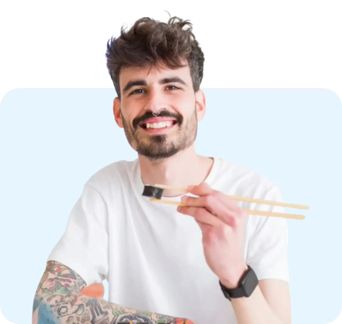 Young man with chopsticks eating sushi